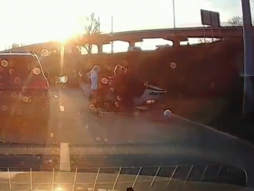 Толпа людей собралась у перевернутой на крышу машины на съезде с воронежского моста 